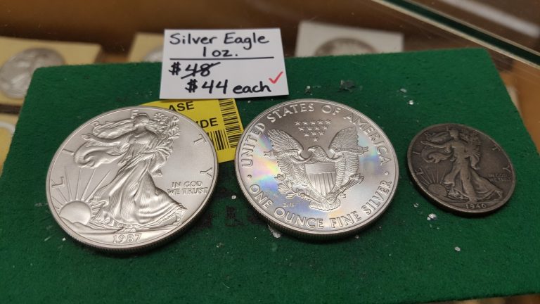 A 1987 Silver Eagle and reverse beside a smaller 1940 Walking Liberty half