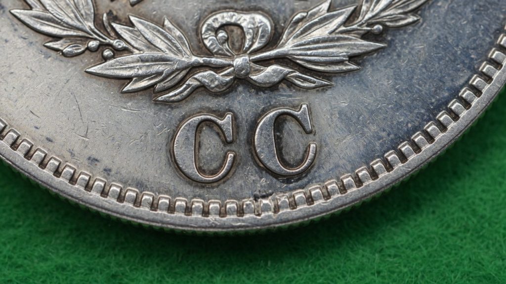 Macro of a CC mint mark on a Morgan dollar reverse on green felt