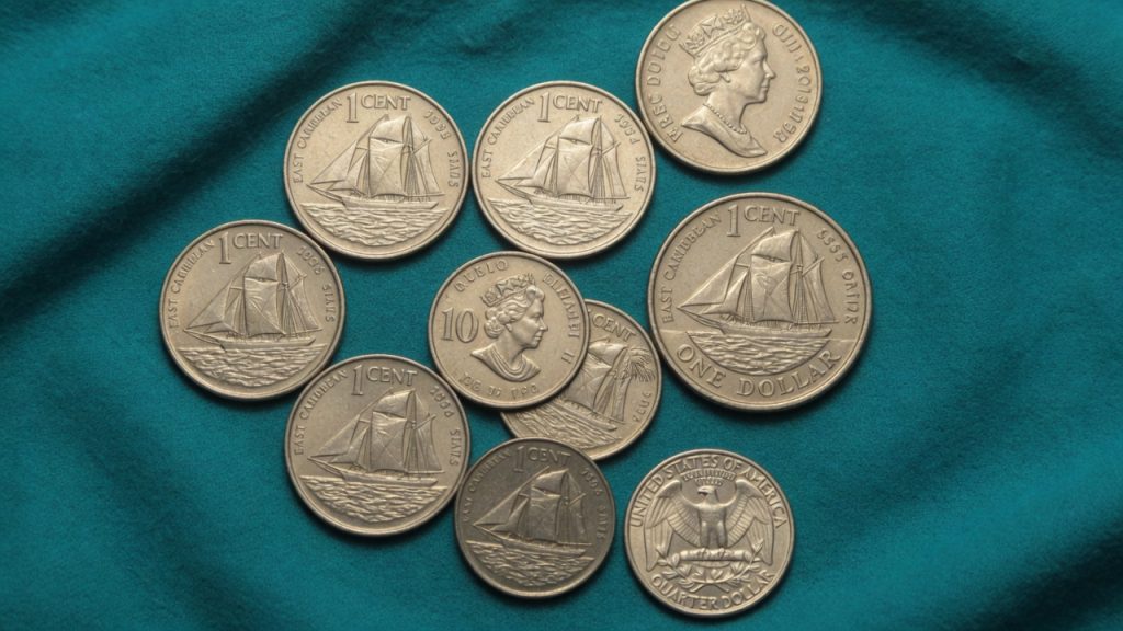 East Caribbean 1-cent sailing-ship coins and a Queen 10-cent piece next to a US quarter