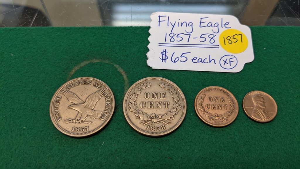 Flying Eagle cents next to a modern Lincoln cent on green felt