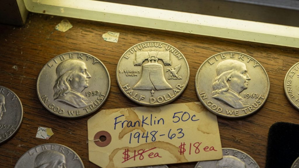 1952 and 1963 Franklin halves with a Liberty Bell reverse on a wooden counter