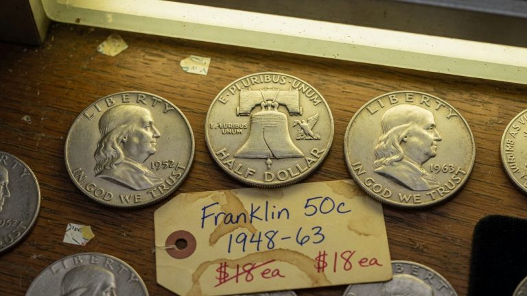 1952 and 1963 Franklin halves with a Liberty Bell reverse on a wooden counter
