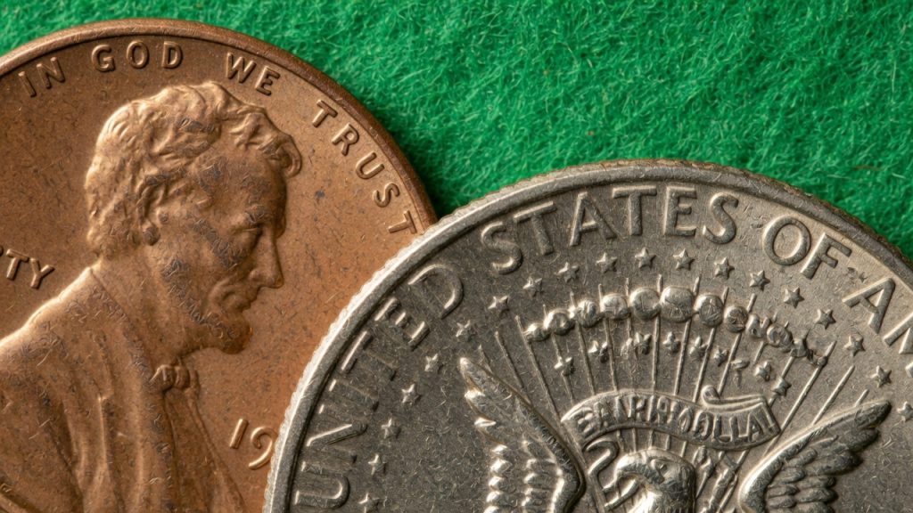Close-up of IN GOD WE TRUST and E PLURIBUS UNUM on United States coins on green felt