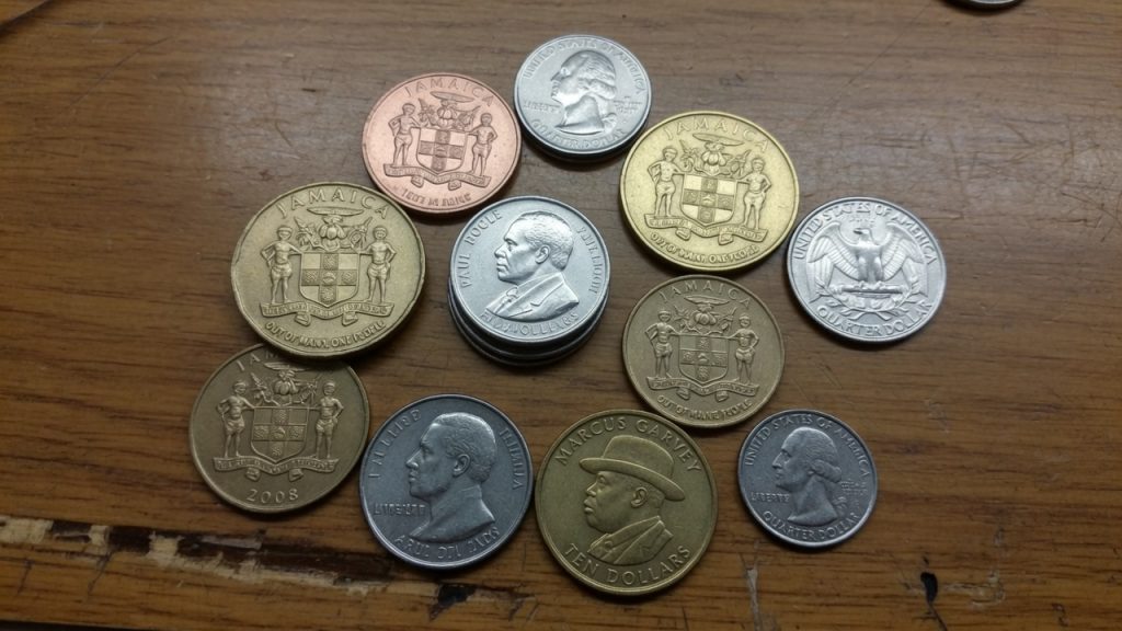 Jamaica circulating coins with the coat of arms, Marcus Garvey, and US quarters for scale