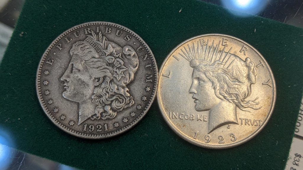 A 1921 Morgan silver dollar next to a Peace dollar on green felt