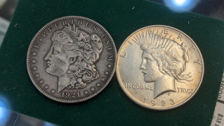 A 1921 Morgan silver dollar next to a Peace dollar on green felt