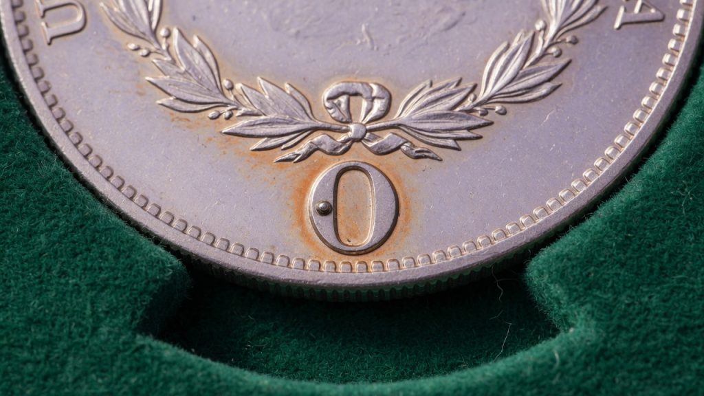 Macro of an O mint mark on a Morgan dollar reverse on green felt