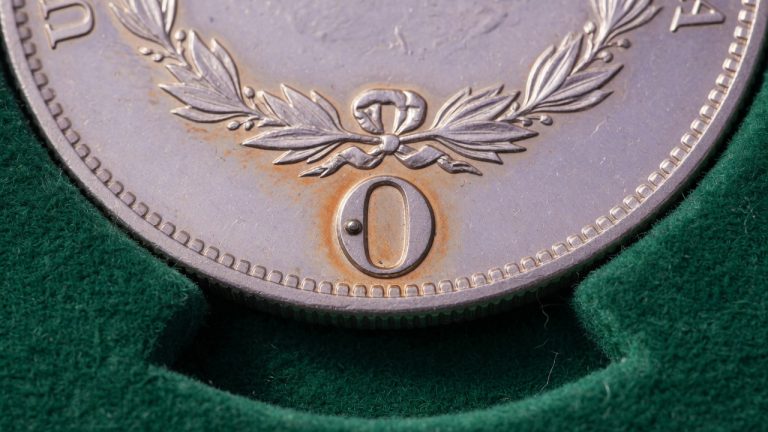 Macro of an O mint mark on a Morgan dollar reverse on green felt