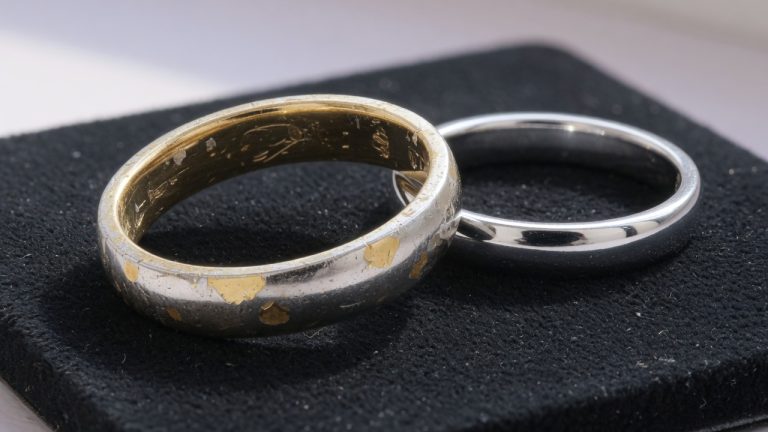 A worn white-gold wedding band with yellow gold showing through the rhodium plate, next to a bright unused white ring