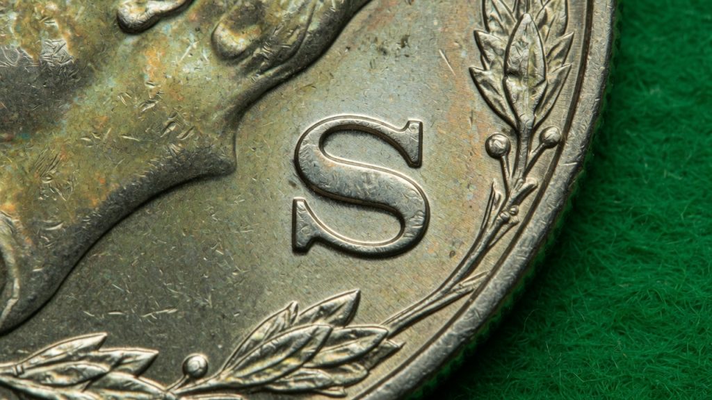 Macro of an S mint mark on a Morgan dollar reverse on green felt