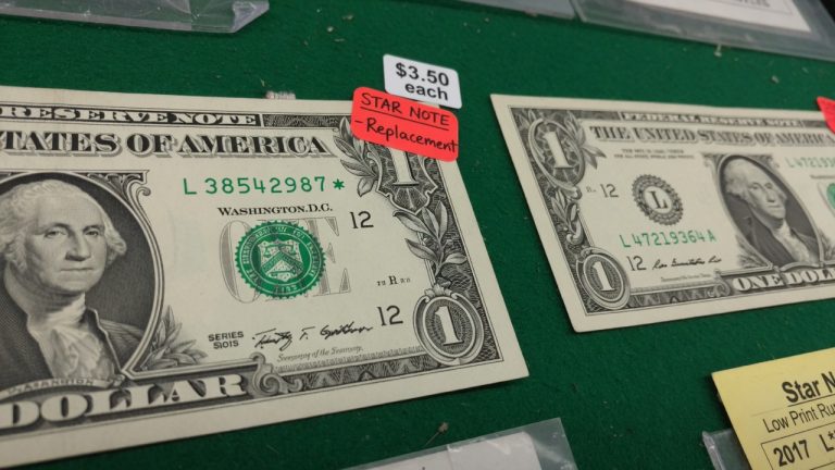 A one-dollar Federal Reserve note with a star at the end of the serial number next to a regular note