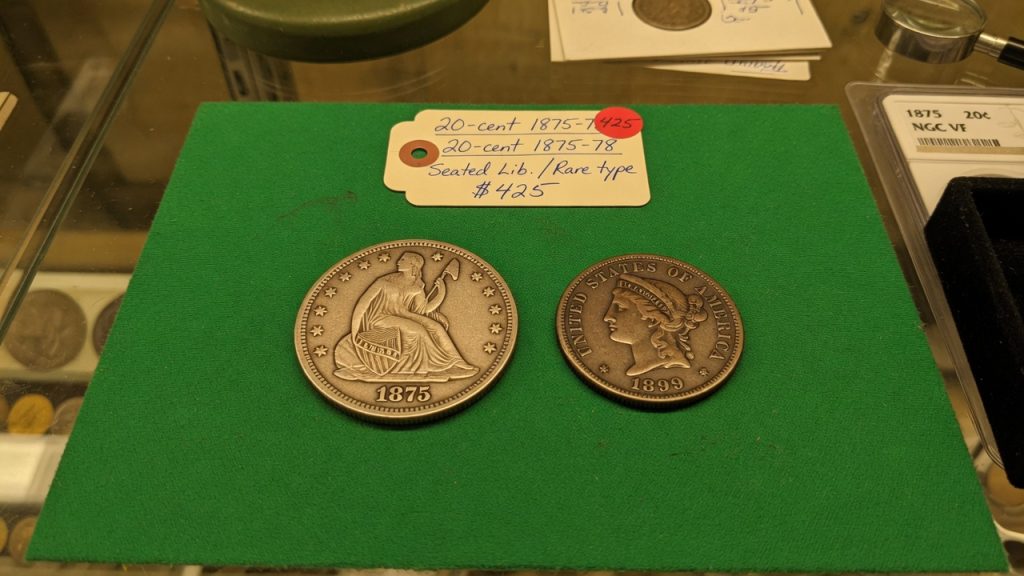 A twenty-cent piece next to a quarter on green felt