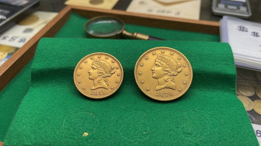 Two small United States gold dollars on green felt